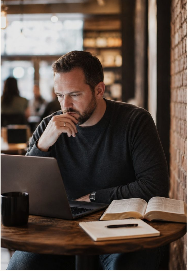 Preacher preparing a sermon with a Bible and laptop